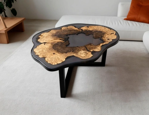 Авторский черный журнальный стол из спила клёна и смолы, расположенный рядом с мягким диваном в зоне отдыха.