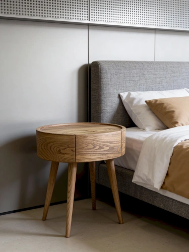 Дизайнерская овальная тумба Ellipse из массива карагача в светлом интерьере современной спальни рядом с кроватью