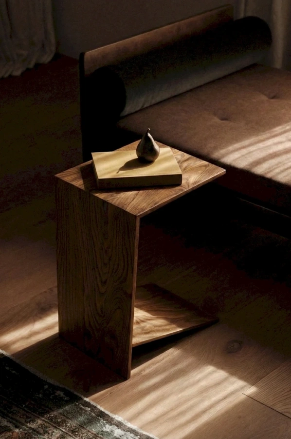 Небольшой деревянный столик у кровати с книгой и ноутбуком