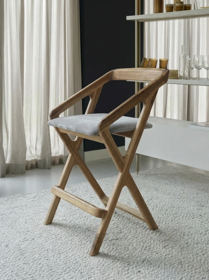 Барный стул с деревянными подлокотниками и светлой тканевой обивкой на фоне интерьера