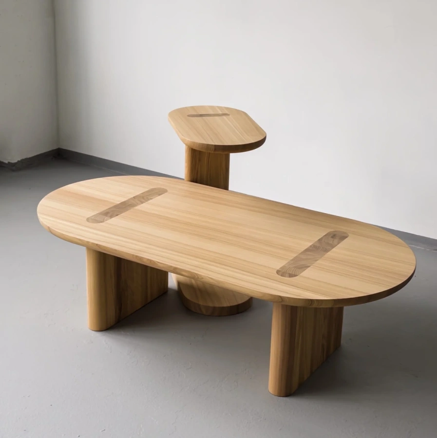 Боковой вид журнального стола Друг, демонстрирующий массивные ножки и плавные овальные формы.