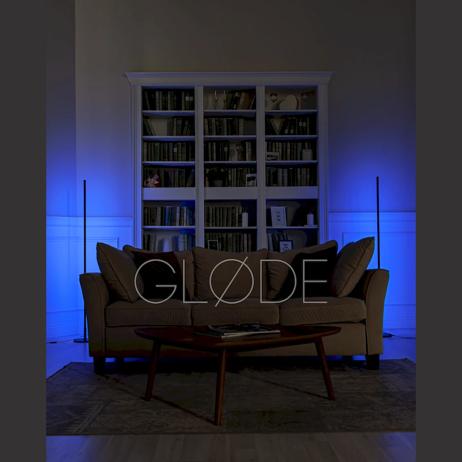 Высокий торшер ColorConer на фоне книжного шкафа светит белым светом