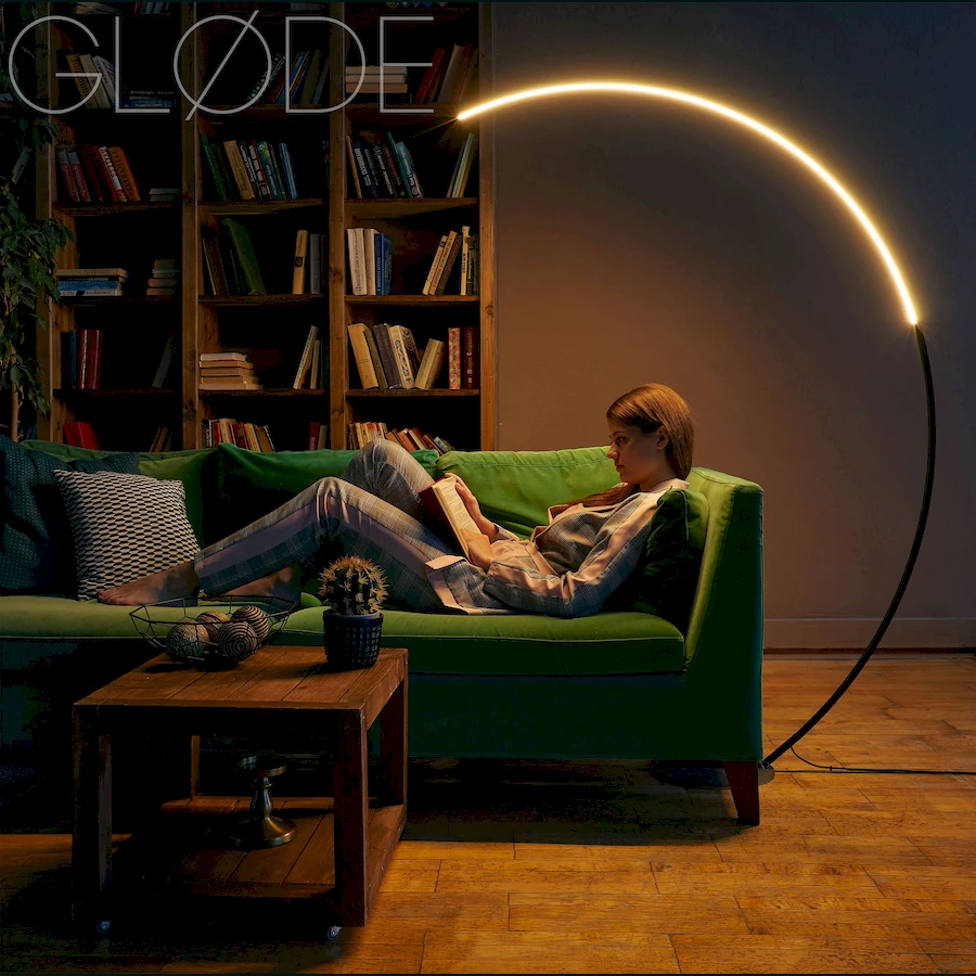 Современный торшер ArcOsmo с дугообразной алюминиевой стойкой в интерьере кабинета девушкой